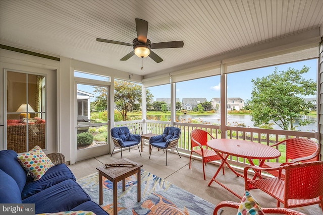 sunroom with ceiling fan and a water view