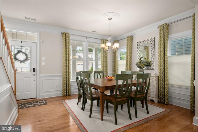 dining area featuring wood-type flooring, a wealth of natural light, and crown molding