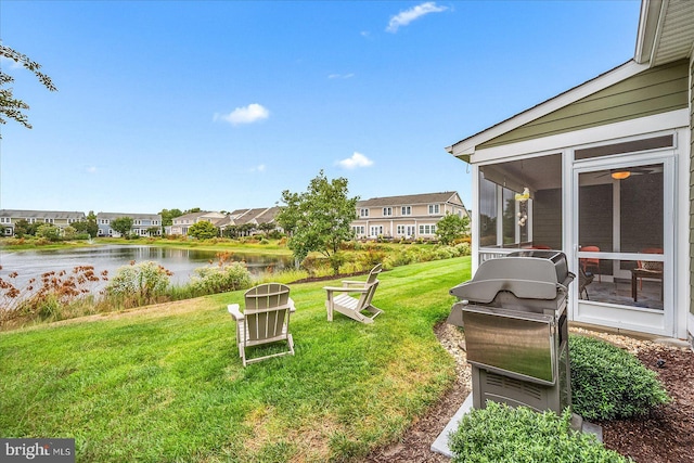 view of yard with a residential view, a sunroom, and a water view