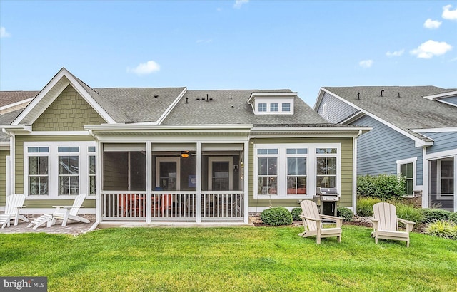 rear view of property featuring a yard, roof with shingles, a patio area, and a sunroom