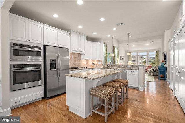 kitchen featuring light hardwood / wood-style flooring, a breakfast bar, appliances with stainless steel finishes, and white cabinetry