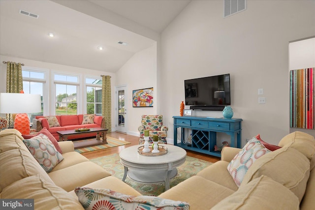 living room with hardwood / wood-style floors and high vaulted ceiling