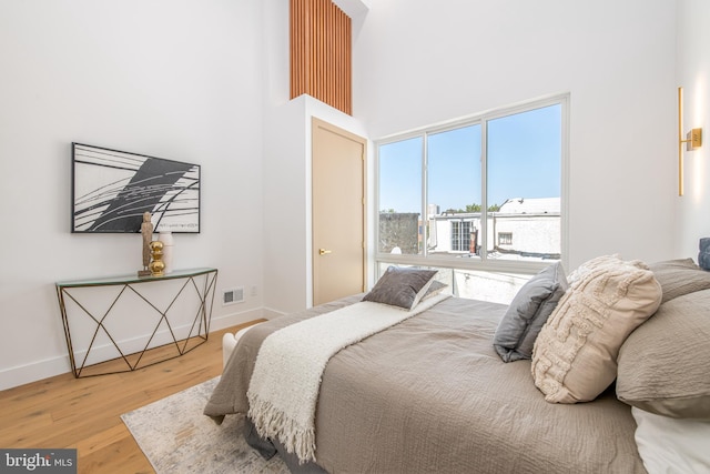 bedroom with a towering ceiling and light hardwood / wood-style flooring