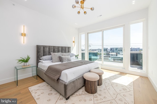 bedroom featuring multiple windows, light hardwood / wood-style flooring, and a chandelier