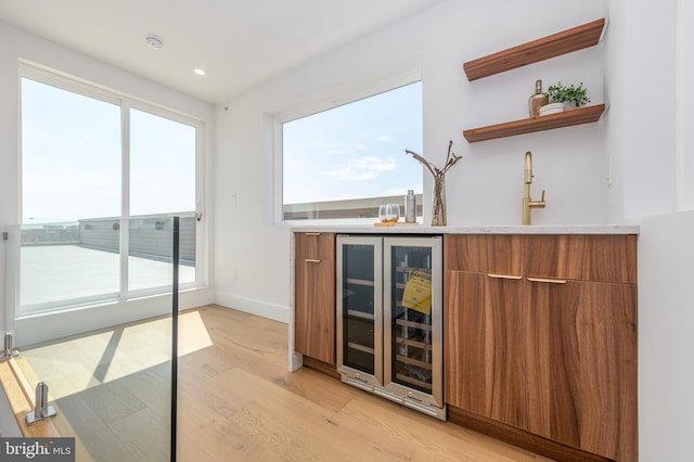 bar featuring beverage cooler, light hardwood / wood-style floors, and sink