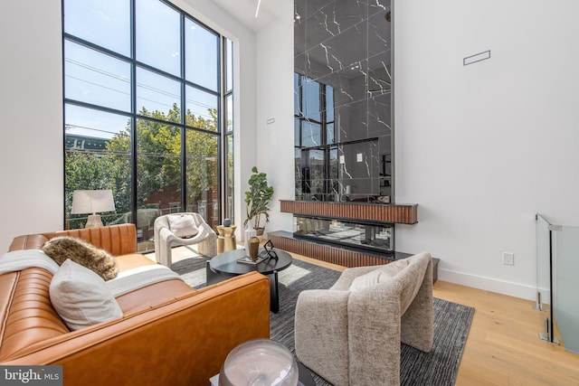 living room featuring a high ceiling, a fireplace, and light hardwood / wood-style floors