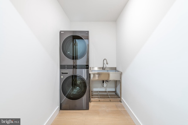 washroom featuring stacked washer / dryer, light hardwood / wood-style flooring, and sink