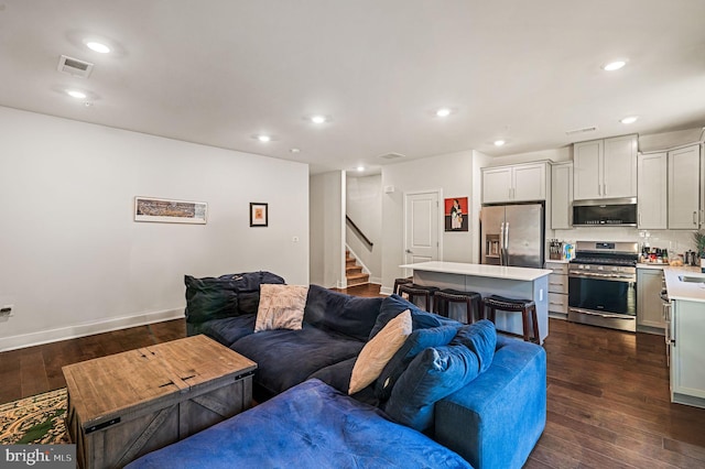 living room with dark wood-style floors, visible vents, stairway, and recessed lighting