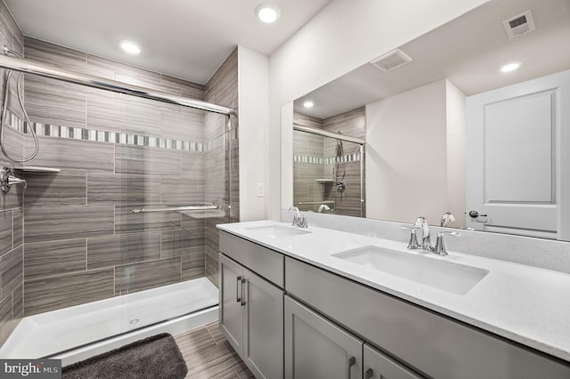 bathroom featuring a shower with door and vanity