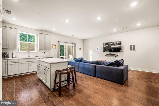 kitchen with a center island, visible vents, decorative backsplash, dark wood-type flooring, and open floor plan