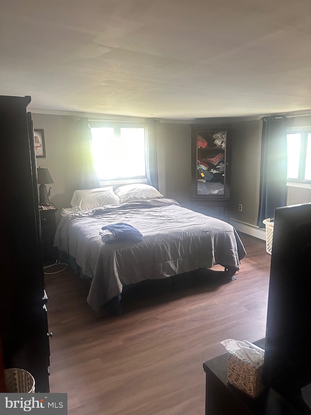 bedroom with dark wood-type flooring and a baseboard radiator