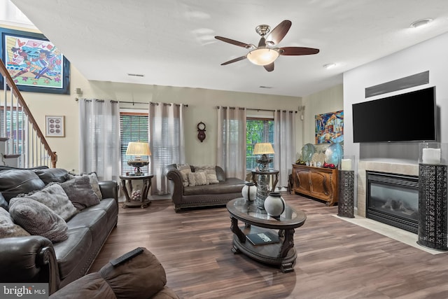 living room featuring ceiling fan, a tile fireplace, dark hardwood / wood-style flooring, and a healthy amount of sunlight