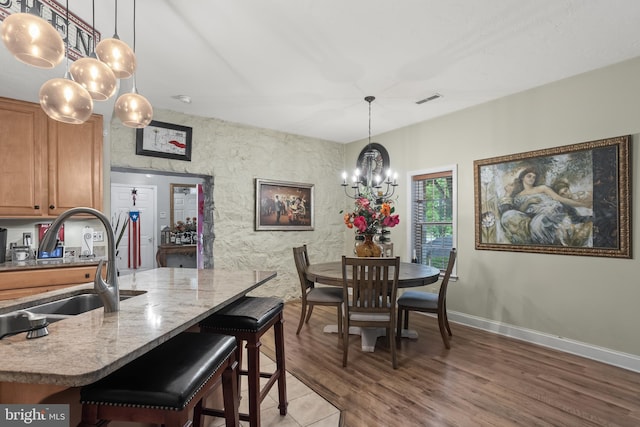 dining space with an inviting chandelier, wood-type flooring, and sink