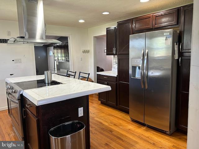 14352 Charmian Rd, Waynesboro, PA 17268 - kitchen with island exhaust hood, dark brown cabinetry, appliances with stainless steel finishes, and light wood-style floors