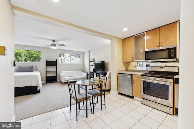 kitchen with light tile patterned flooring, light carpet, baseboards, open floor plan, and appliances with stainless steel finishes