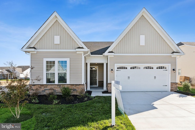 craftsman house with an attached garage, driveway, stone siding, a front lawn, and board and batten siding