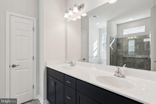 full bath with visible vents, a sink, a shower stall, and double vanity