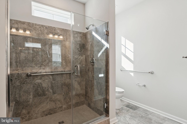 full bathroom with toilet, a shower stall, and baseboards