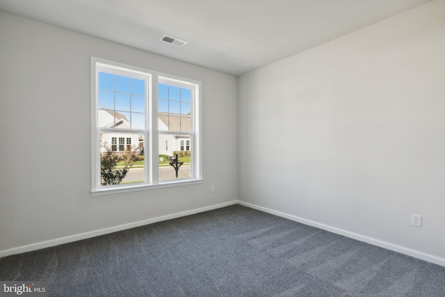 unfurnished room with dark colored carpet, visible vents, and baseboards