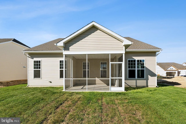 back of house featuring a shingled roof, a sunroom, and a yard