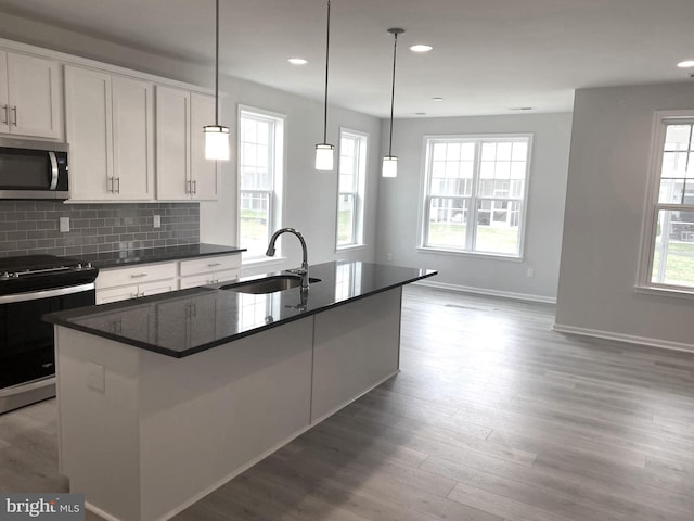 kitchen with white cabinetry, a kitchen island with sink, stove, light wood-type flooring, and sink