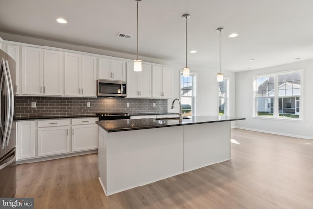 kitchen featuring visible vents, appliances with stainless steel finishes, a sink, white cabinetry, and backsplash