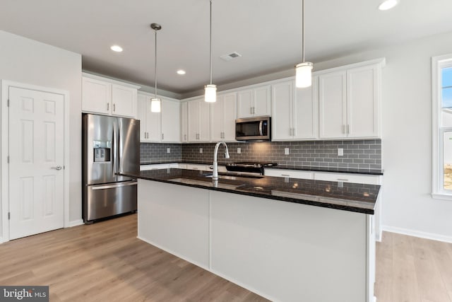 kitchen featuring light wood-style flooring, a sink, white cabinets, appliances with stainless steel finishes, and decorative backsplash