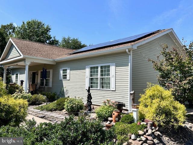 view of home's exterior featuring a shingled roof and roof mounted solar panels