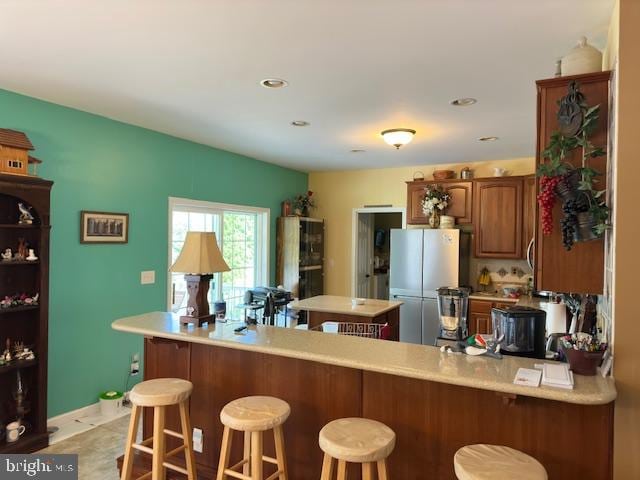 kitchen featuring stainless steel fridge, kitchen peninsula, and a kitchen bar