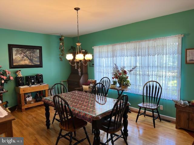 dining area featuring a chandelier, wood finished floors, and baseboards