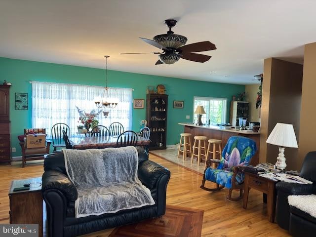 living room featuring light wood-type flooring and ceiling fan with notable chandelier