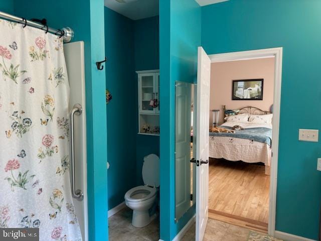 full bath with a shower with shower curtain, baseboards, toilet, and ensuite bathroom