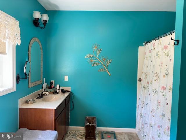 bathroom with a shower with shower curtain, vanity, and baseboards