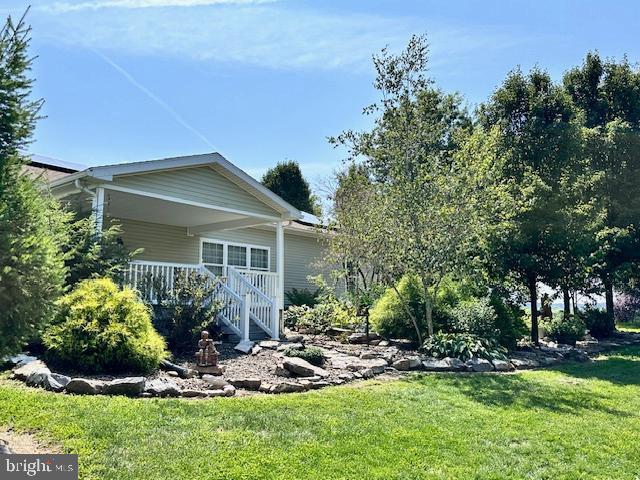 view of side of home featuring a porch and a yard