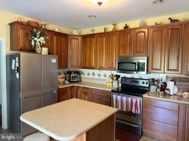 kitchen with backsplash, a kitchen island, and stainless steel appliances