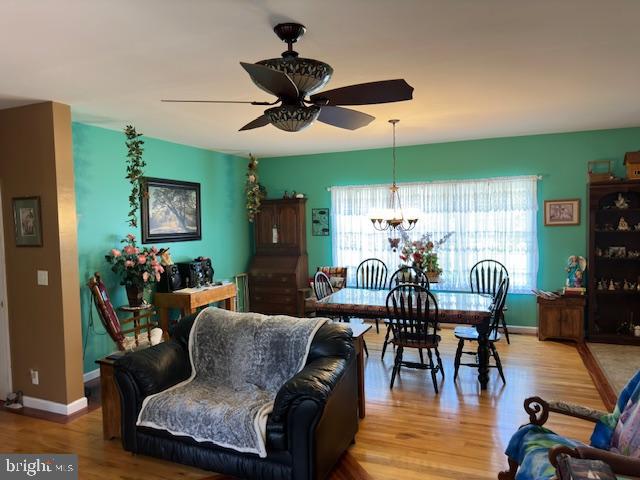 living room with ceiling fan with notable chandelier and hardwood / wood-style flooring