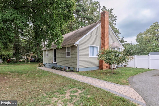 view of property exterior with a yard, fence, and a chimney