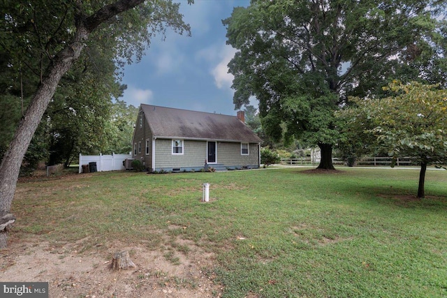 exterior space with fence, a chimney, and a front lawn