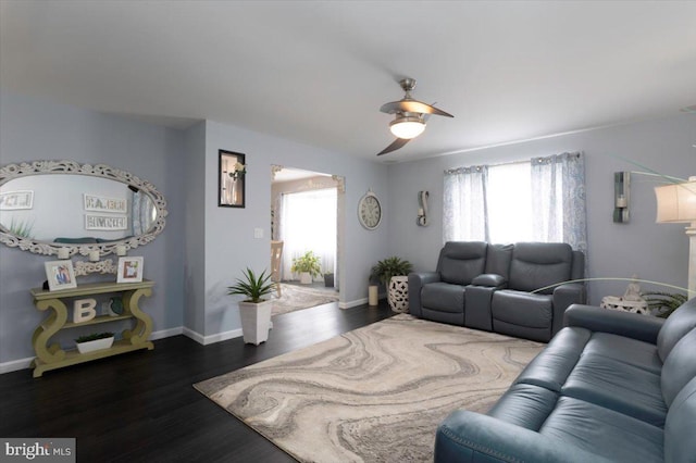 living room with a ceiling fan, baseboards, and wood finished floors