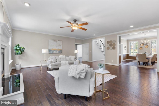 living room with dark wood-type flooring, ceiling fan with notable chandelier, and ornamental molding