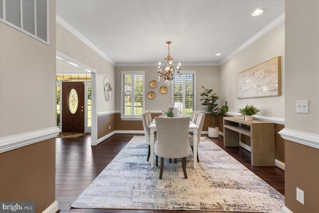 dining room with crown molding, dark wood-type flooring, and an inviting chandelier