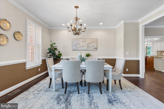 dining area with ornamental molding, dark wood-type flooring, and an inviting chandelier