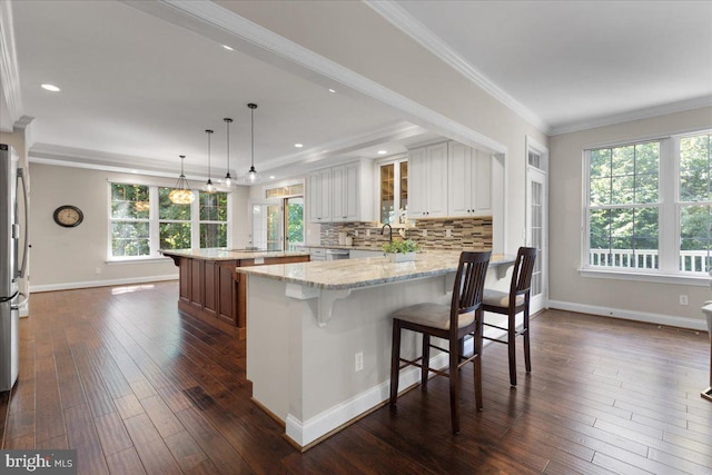 kitchen featuring light stone countertops, plenty of natural light, white cabinets, and a kitchen island