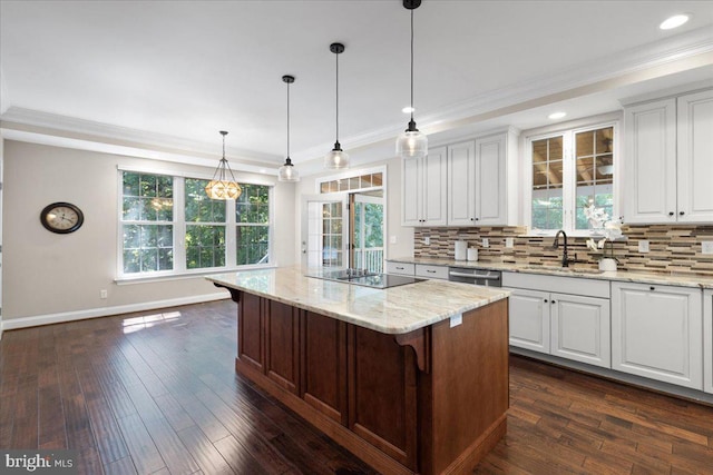 kitchen featuring white cabinets, light stone counters, a kitchen island, and a wealth of natural light