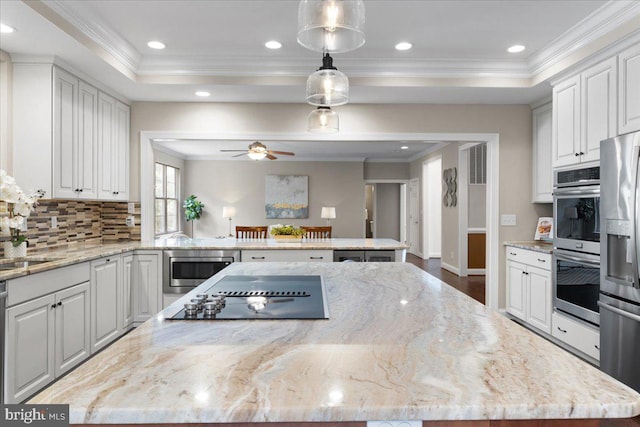 kitchen with light stone counters, white cabinets, and pendant lighting