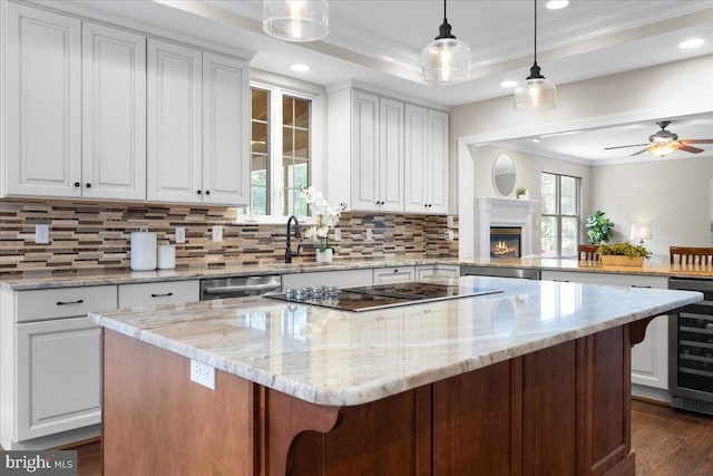 kitchen with kitchen peninsula, light stone counters, white cabinets, and a kitchen island