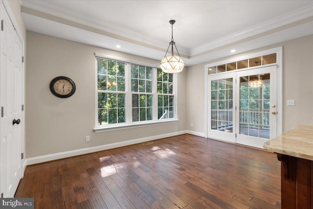 unfurnished dining area with dark wood-type flooring, crown molding, a tray ceiling, and a healthy amount of sunlight