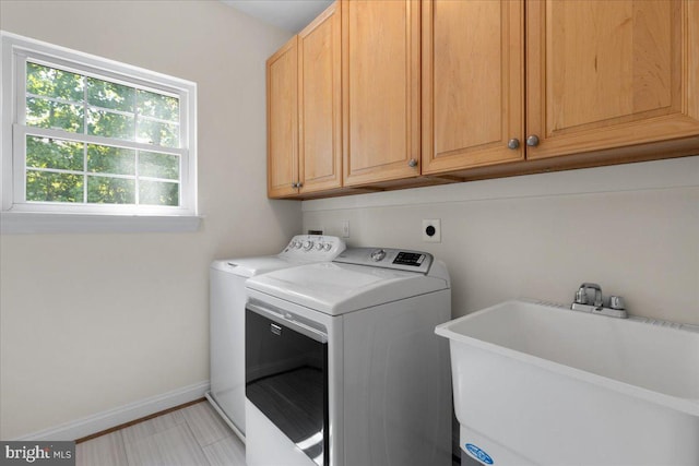 clothes washing area featuring cabinets, washer and clothes dryer, and sink