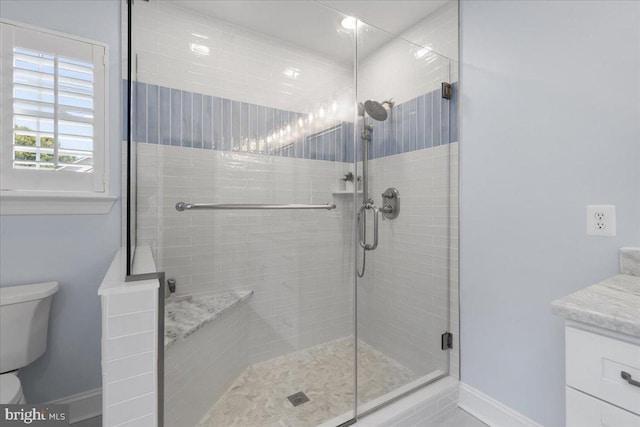 bathroom with vanity, toilet, and a shower with door