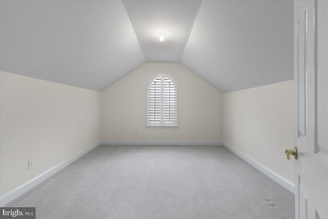 additional living space featuring light colored carpet and lofted ceiling